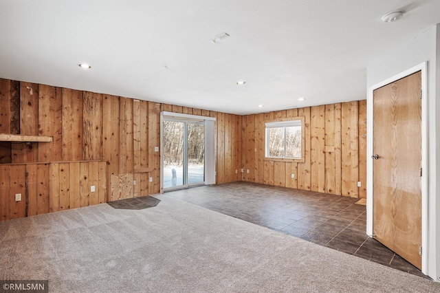 unfurnished room featuring dark carpet and wood walls