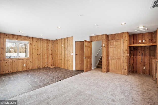 carpeted spare room with wooden walls