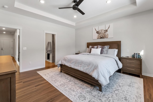 bedroom featuring a walk in closet, ceiling fan, and a tray ceiling