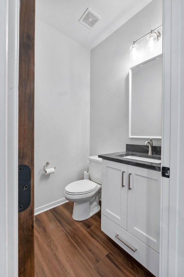 bathroom with vanity, hardwood / wood-style flooring, a textured ceiling, and toilet