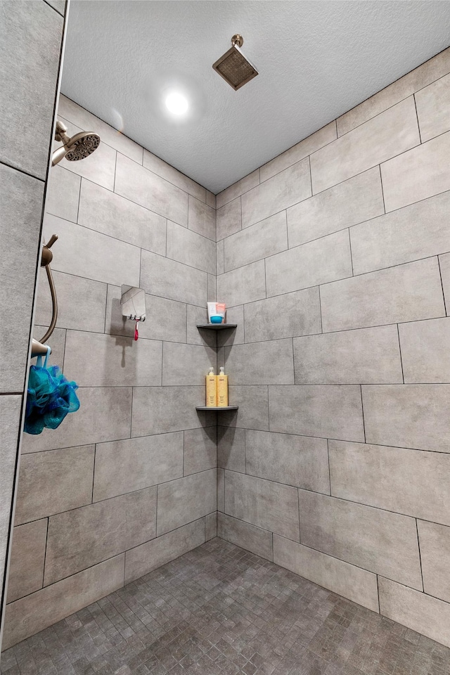 bathroom featuring a textured ceiling and a tile shower