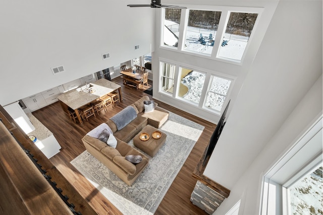 living room featuring hardwood / wood-style flooring, ceiling fan, and a high ceiling