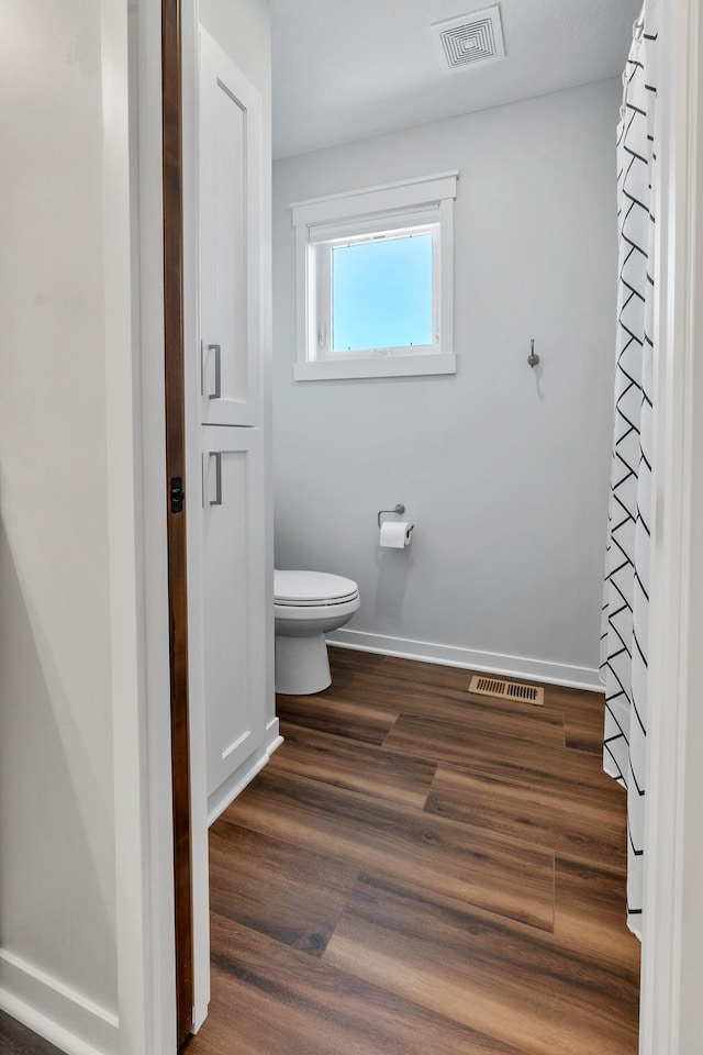 bathroom with hardwood / wood-style flooring and toilet