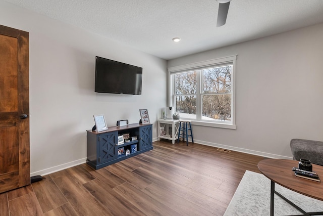 living room with ceiling fan, dark hardwood / wood-style floors, and a textured ceiling