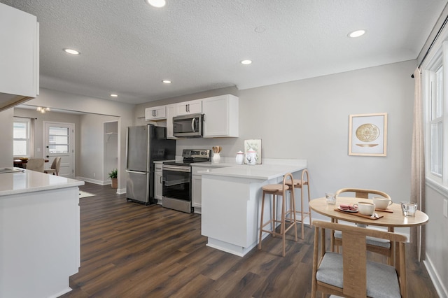 kitchen featuring white cabinetry, dark wood-type flooring, stainless steel appliances, and kitchen peninsula