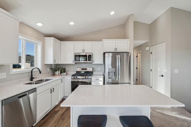 kitchen featuring sink, white cabinetry, a center island, vaulted ceiling, and stainless steel appliances