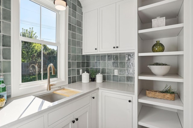 kitchen with backsplash, sink, and white cabinets