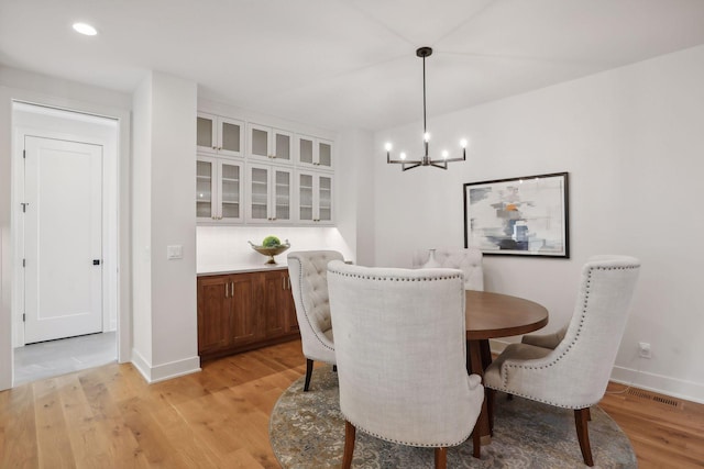 dining room with light hardwood / wood-style flooring and a notable chandelier