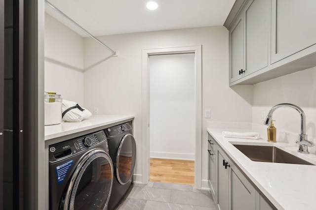 washroom with cabinets, washer and clothes dryer, and sink