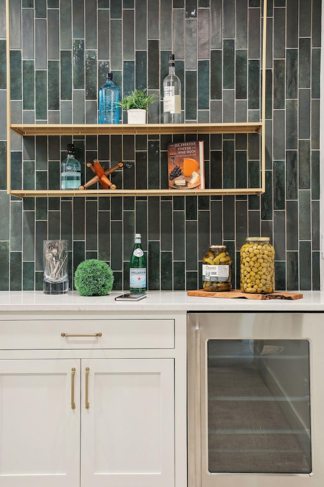 interior space featuring decorative backsplash, beverage cooler, and white cabinets