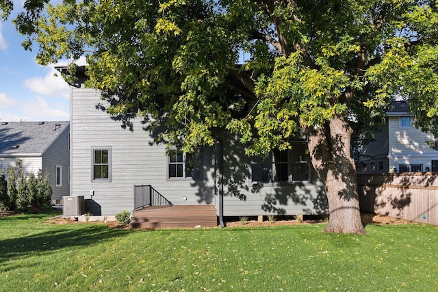 rear view of house featuring central AC and a lawn