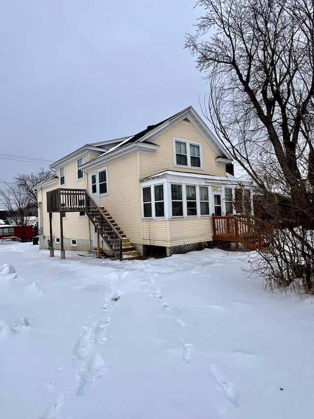 snow covered back of property featuring a wooden deck