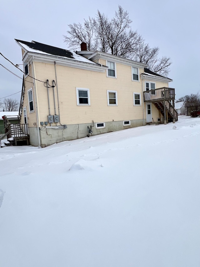 snow covered house featuring a wooden deck