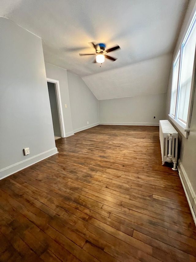 additional living space with ceiling fan, radiator heating unit, dark hardwood / wood-style flooring, and vaulted ceiling