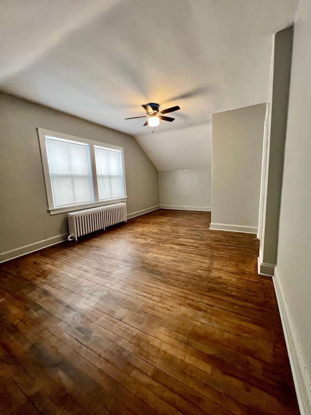 additional living space with vaulted ceiling, dark hardwood / wood-style flooring, radiator, and ceiling fan