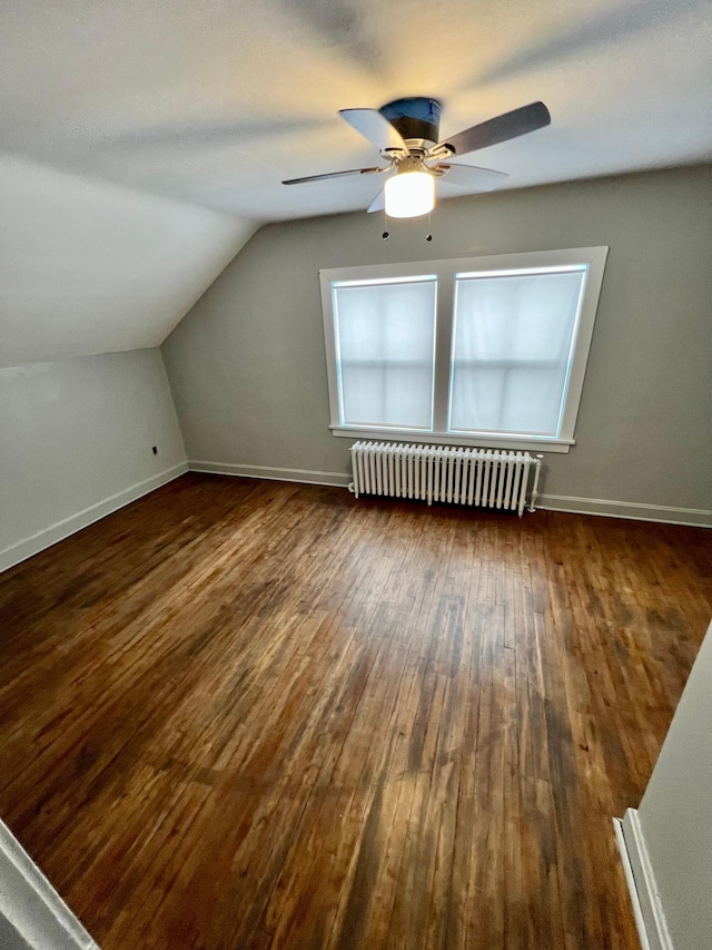 additional living space with lofted ceiling, radiator heating unit, dark hardwood / wood-style floors, and ceiling fan