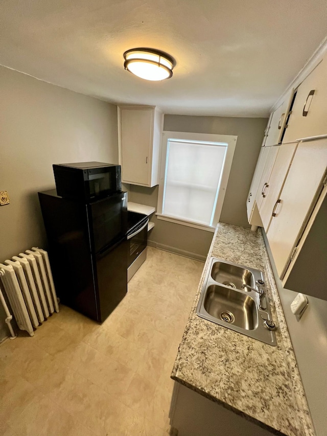 kitchen with white cabinetry, sink, radiator heating unit, and black appliances