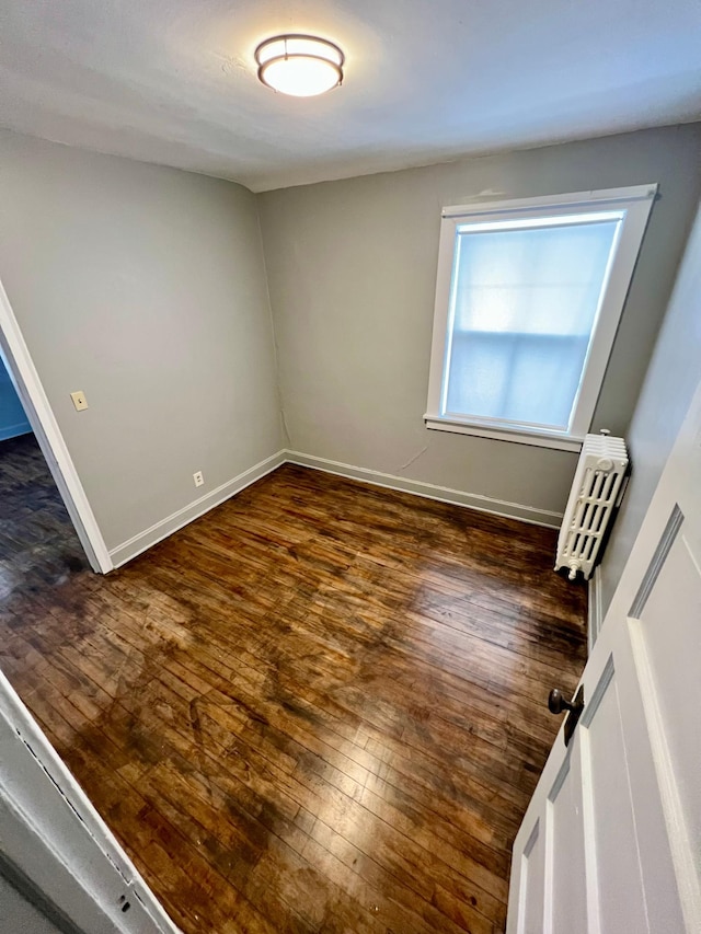 unfurnished room with radiator and dark hardwood / wood-style flooring