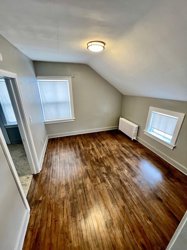 bonus room with lofted ceiling, radiator heating unit, and dark hardwood / wood-style flooring