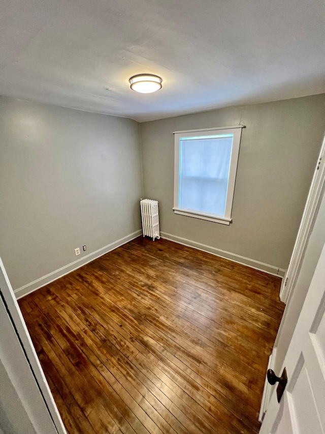 spare room featuring dark wood-type flooring and radiator heating unit