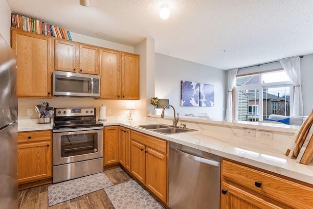kitchen with dark wood finished floors, stainless steel appliances, a textured ceiling, and a sink