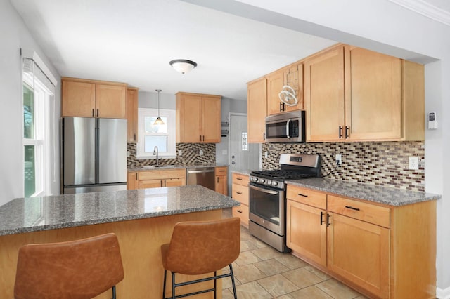 kitchen featuring tasteful backsplash, dark stone counters, a kitchen breakfast bar, stainless steel appliances, and a sink