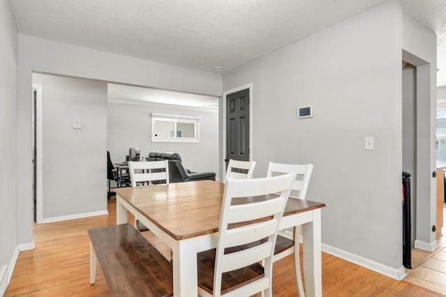 dining space featuring light wood finished floors and baseboards