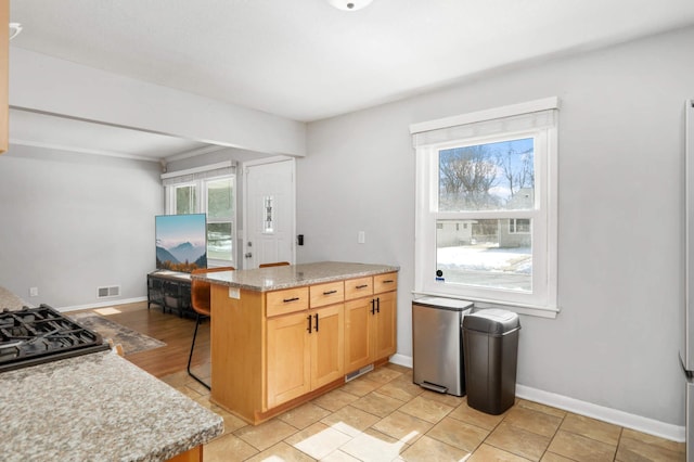 kitchen featuring visible vents, baseboards, a peninsula, and a breakfast bar area