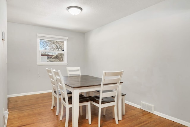 dining space with visible vents, baseboards, and light wood-style flooring