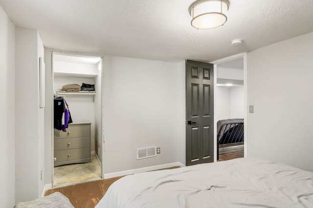 bedroom with baseboards, visible vents, a spacious closet, a closet, and a textured ceiling