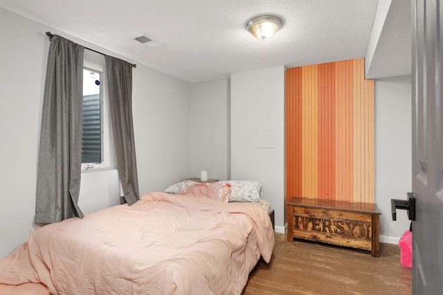 bedroom with visible vents, baseboards, and wood finished floors