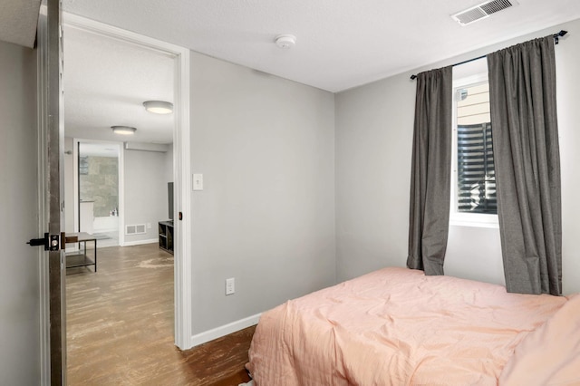 bedroom with dark wood-style floors, visible vents, and baseboards