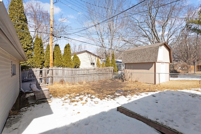 yard layered in snow featuring a storage shed, an outbuilding, and a fenced backyard