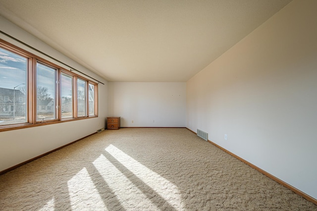 carpeted empty room with visible vents and baseboards