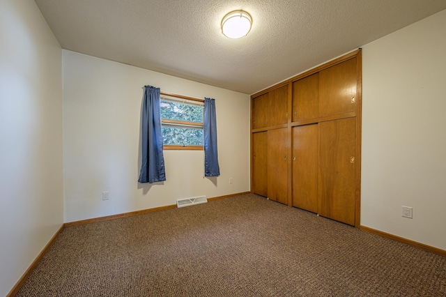 unfurnished bedroom with a textured ceiling, carpet flooring, visible vents, and baseboards