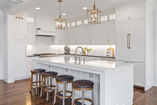 kitchen with premium range hood, pendant lighting, white cabinets, dark hardwood / wood-style flooring, and a center island with sink