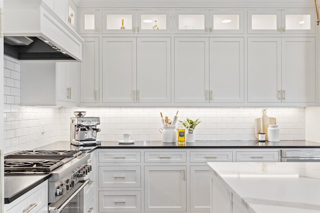 kitchen with custom exhaust hood, stainless steel range, and white cabinets