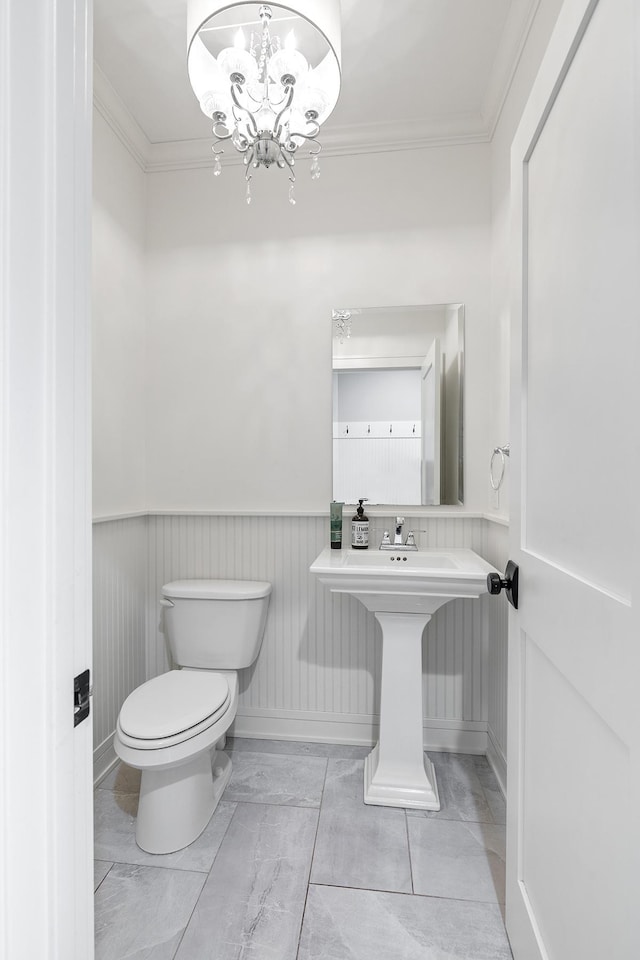 bathroom featuring ornamental molding, toilet, and a notable chandelier