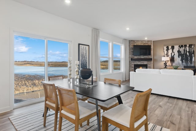 dining space featuring a stone fireplace and light wood-type flooring