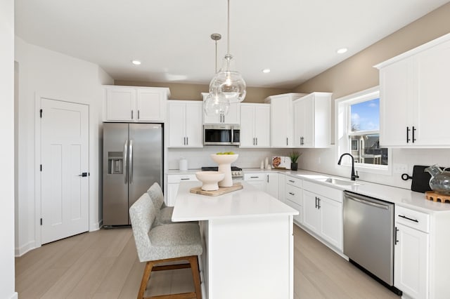 kitchen with backsplash, appliances with stainless steel finishes, white cabinets, a sink, and a kitchen island