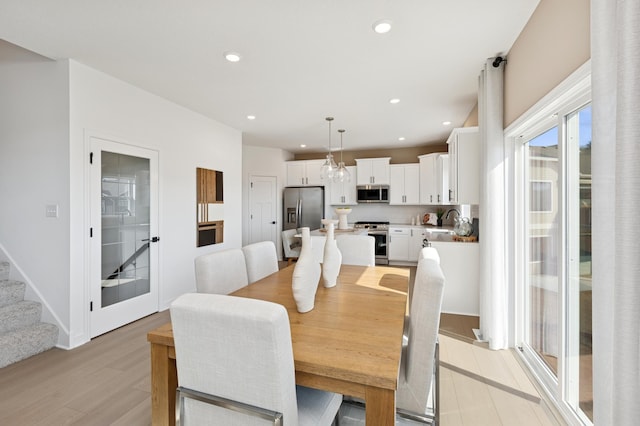 dining space with stairs, light wood finished floors, baseboards, and recessed lighting