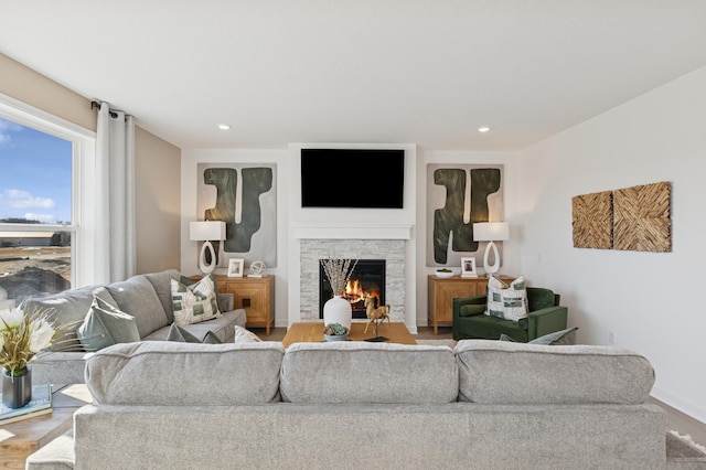 living room featuring recessed lighting, a stone fireplace, and wood finished floors