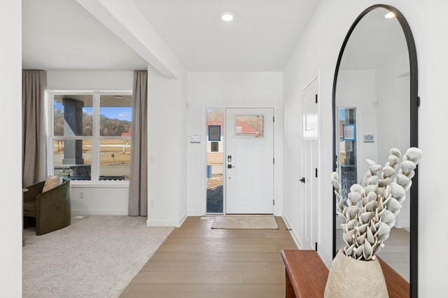 foyer entrance featuring arched walkways, recessed lighting, carpet flooring, wood finished floors, and baseboards