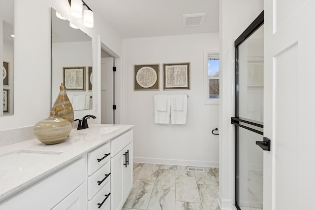 bathroom featuring marble finish floor, double vanity, a sink, and visible vents