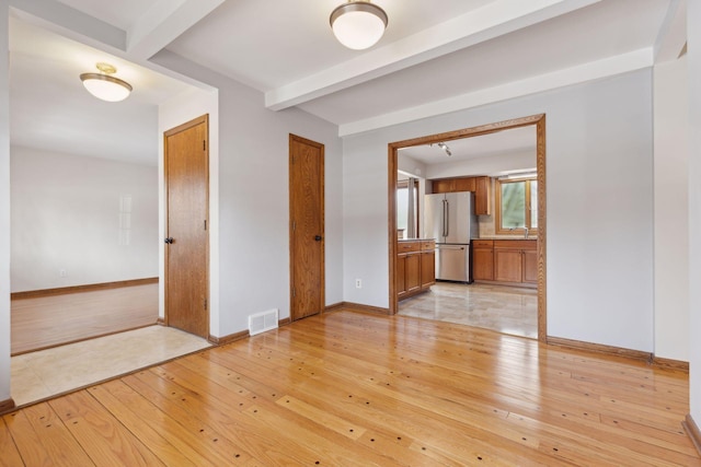 spare room with beam ceiling, sink, and light hardwood / wood-style flooring