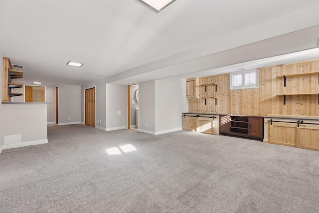 interior space with light colored carpet and wood walls