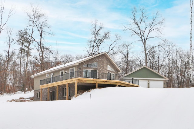 snow covered rear of property with an outbuilding and a garage