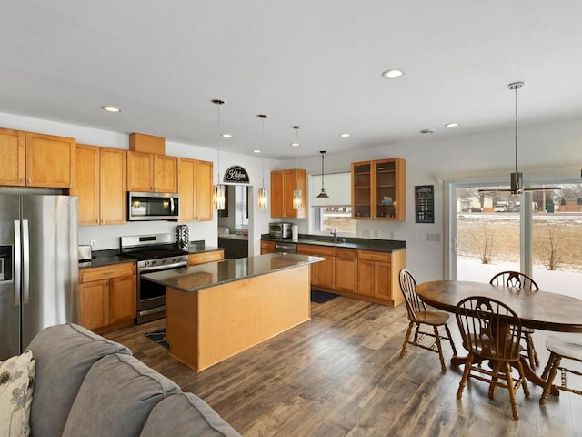 kitchen featuring a sink, glass insert cabinets, dark countertops, and appliances with stainless steel finishes