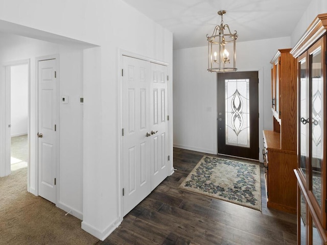 entryway with baseboards, an inviting chandelier, and dark wood-style floors