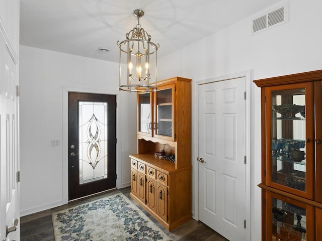 foyer entrance with dark wood-style floors, visible vents, baseboards, and an inviting chandelier